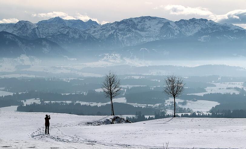 Ein Spaziergängerin fotografiert am 31.01.2014 auf dem Auerberg bei Stötten das Panorama der Alpen