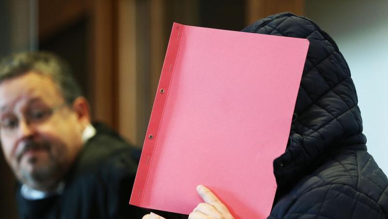Der Angeklagte im Prozess wegen schweren sexuellen Missbrauchs hält sich im Gerichtssaal eine Mappe vor das Gesicht.