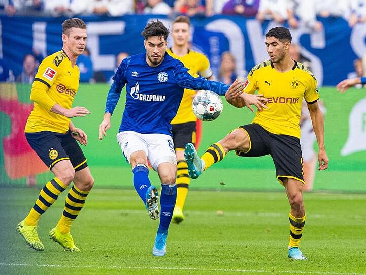 Dortmunds Achraf Hakimi (r) und Lukasz Piszczek (l) nehmen Schalkes Suat Serdar in die Zange.