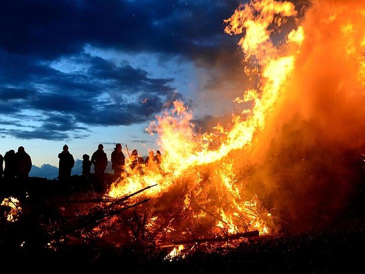 Menschen stehen um ein traditionelles Osterfeuer. Foto: Maurizio Gambarini/Archivbild