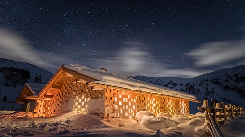 Ein verschneites Chalet unter Sternenhimmel.