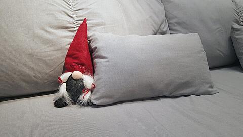Ein kleiner Weihnachtswichtel sitzt auf einem Sofa.