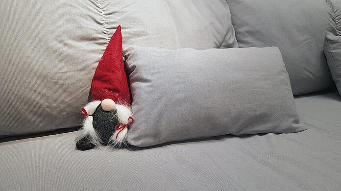 Ein kleiner Weihnachtswichtel sitzt auf einem Sofa.