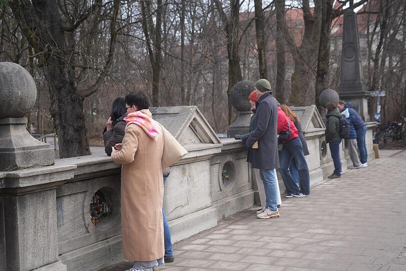 Immer wieder schauen Besucher von der Eisbachbr&uuml;cke aufs Wasser. Nur: Wellenreiter sind noch immer keine da.