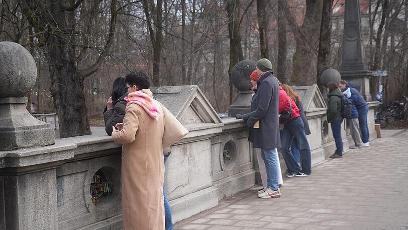 Immer wieder schauen Besucher von der Eisbachbr&uuml;cke aufs Wasser. Nur: Wellenreiter sind noch immer keine da.