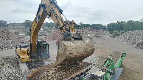Schrittweise Recycling: Die Gesteinkörner, die einst einmal Gebäude wie die im Hintergrund waren, kommen zunächst durch den "Brecher" und werden dort zerkleinert.