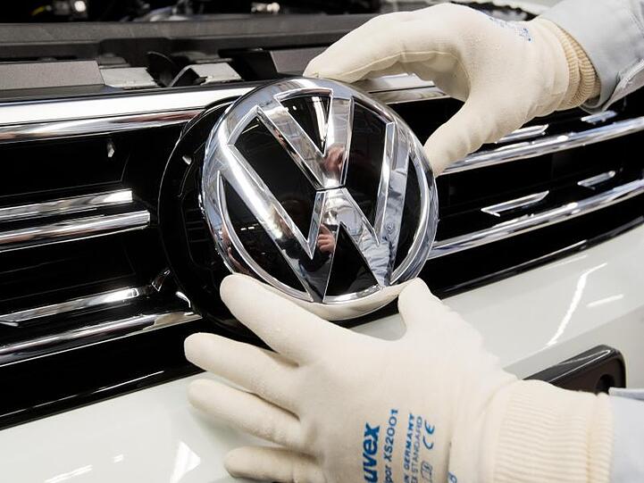 Endmontage im VW-Werk Wolfsburg. Ein Mitarbeiter montiert ein VW Logo an die Front eines VW Tiguan.