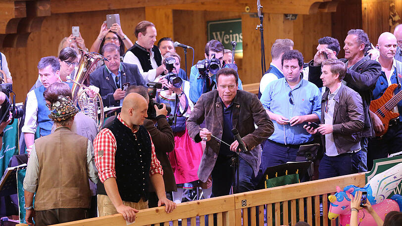 Erst eine kühle Maß, danach Dirigieren auf der Bühne: Die Bilder vom Schwarzenegger-Besuch im Schützen-Festzelt.