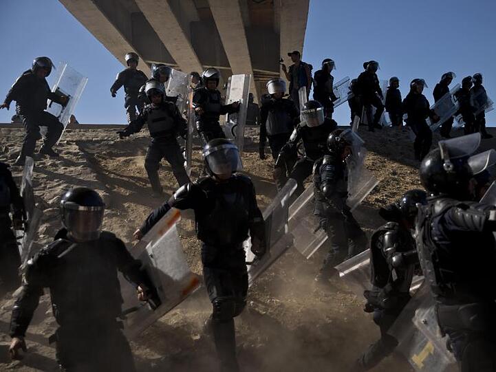 Mexikanische Polizisten versuchen Migranten davon abzuhalten, den Grenzübergang El Chaparral zu den USA zu passieren.
