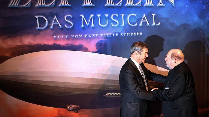 Markus Söder, bayerischer Ministerpräsident und CSU-Vorsitzender (l), wird vor der Weltpremiere des Musicals "Zeppelin", von dessen Komponisten Ralph Siegel, begrüßt.