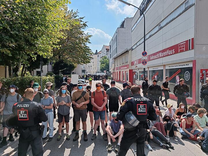 Gleich nach Ankunft der Polizei stehen sich erste Demonstranten und erste Beamte vor dem Haus an der Bavariastraße gegenüber.