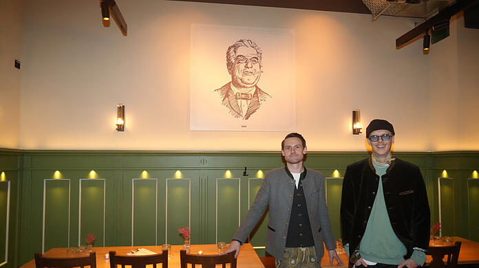 Dennis Dobry (links) und Sebastian Goller in ihrem neu eröffneten Wirtshaus Papa Benz in der Leopoldstraße. Das Bild an der Wand zeigt den Namenspatron Josef Benz, der in diesen Räumen vor 124 Jahren ein Künstlerlokal eröffnete.