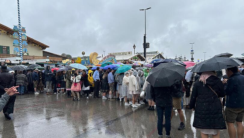 Lange Schlangen vor den Festzelten: Die Besucher der Wiesn lassen sich die gute Stimmung selbst bei strömenden Regen nicht nehmen.