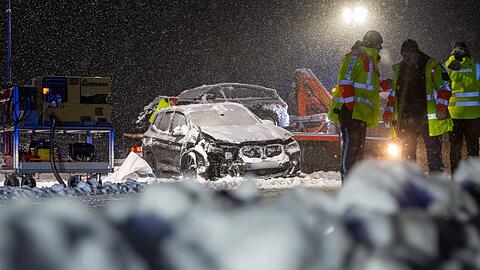 Auf der verschneiten Bundesstra&szlig;e 12 stehen Feuerwehrm&auml;nner an einer Unfallstelle.