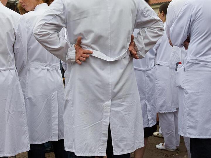 Ärzte in weißen Kitteln stehen in einem Krankenhaus zusammen. Foto: Jens Wolf/Archiv