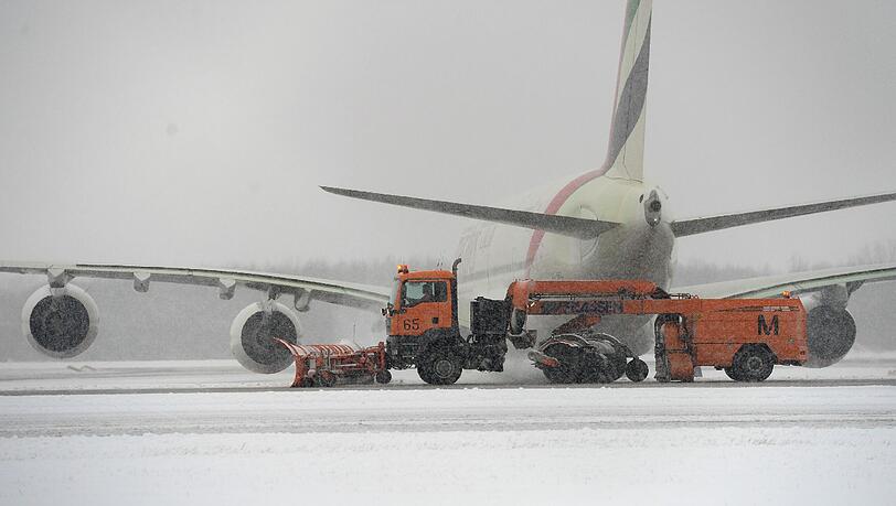 Ein Schneepflug fährt am 30.12.2014 auf dem Flughafen in München an einem parkenden Flugzeug vorbei. (Symbolbild) Ein Schneepflug fährt am 30.12.2014 auf dem Flughafen in München an einem parkenden Flugzeug vorbei. (Symbolbild)