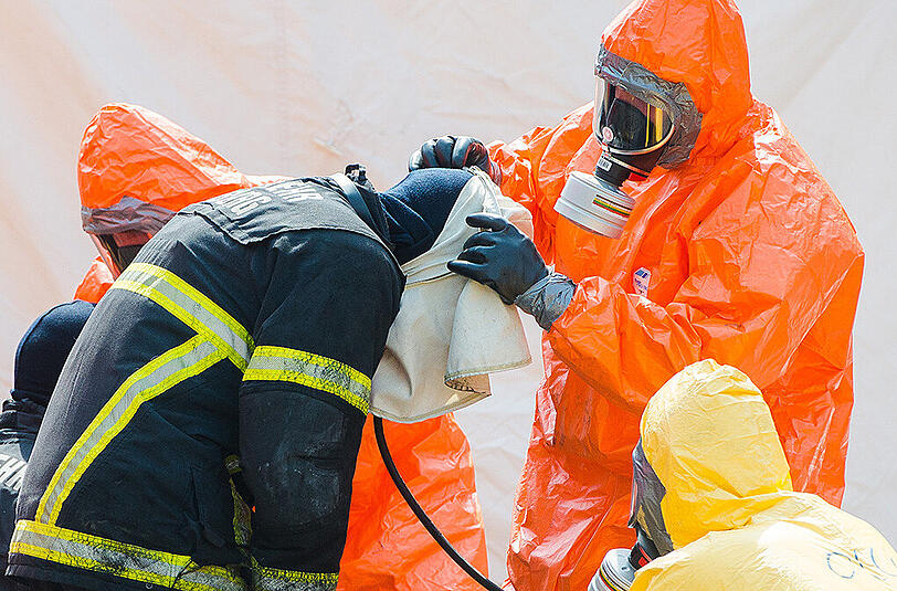 Feuerwehrleute werden nach ihrem Einsatz dekontaminiert.