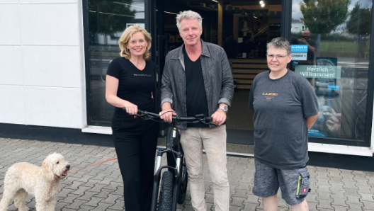 Julia Klöckner und Jörg Pilawa posieren vor einem Fahrradgeschäft neben einer Mitarbeiterin des Ladens.