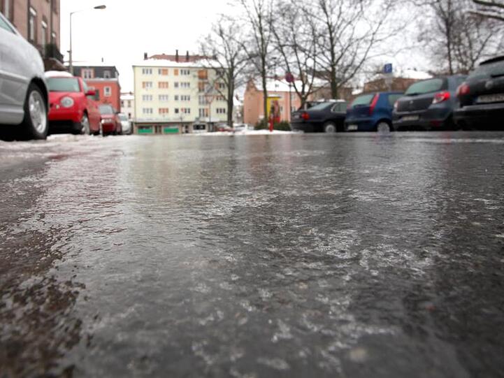Eine Eisschicht bedeckt eine Straße. Foto: Daniel Karmann/Archiv