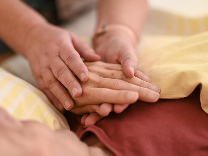 Eine Hospizmitarbeiterin hält die Hand eines todkranken Menschen. Foto: Felix Kästle/dpa/Archivbild
