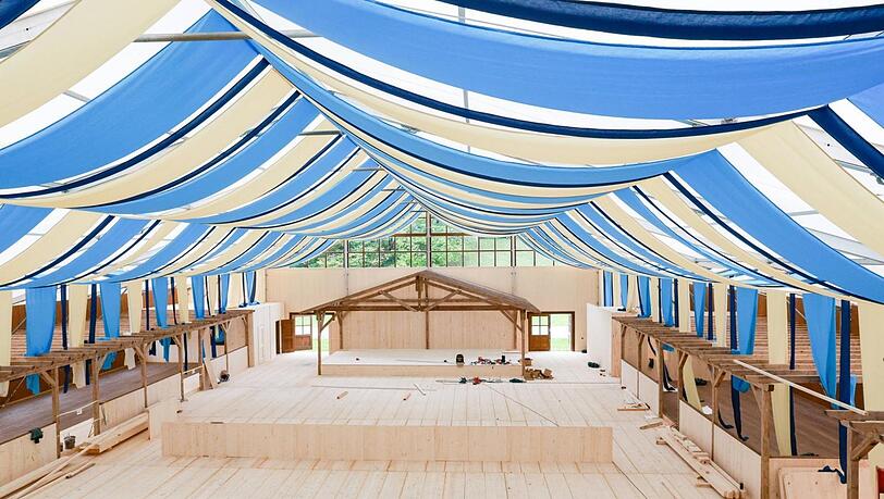 Es lässt sich schon erkennen, welchen Stil das neue Wiesn-Zelt halt. Hier ist viel Holz verbaut, nur ganz so hell bleibt es nicht. Im Moment streichen Maler die Fichtenbretter etwas dunkler an