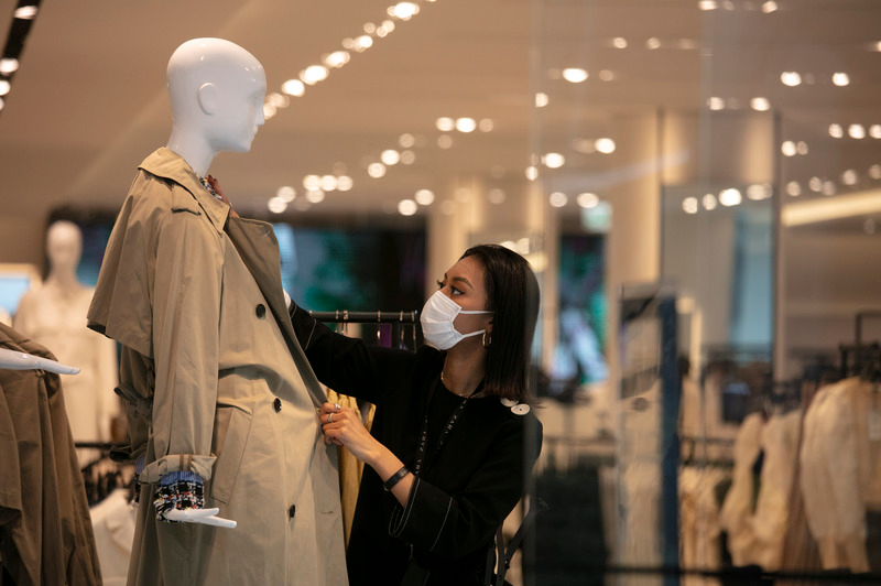Japan, Tokio: Eine Kaufhausangestellte trägt einen Mundschutz, während sie eine Schaufensterpuppe einkleidet.