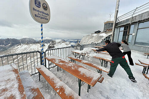 Ein Mann und eine Frau beim Schnee schippen auf der Zugspitze. Und das im September!
