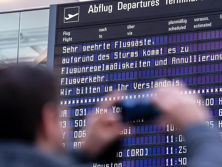 Ein Reisender fotografiert am Münchner Flughafen eine Anzeigetafel mit einem Hinweis. Foto: Matthias Balk/dpa