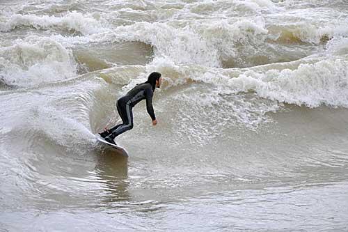 Ein Surfer reitet die "Münchner Welle" an der Reichenbachbrücke