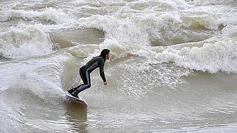Ein Surfer reitet die "Münchner Welle" an der Reichenbachbrücke