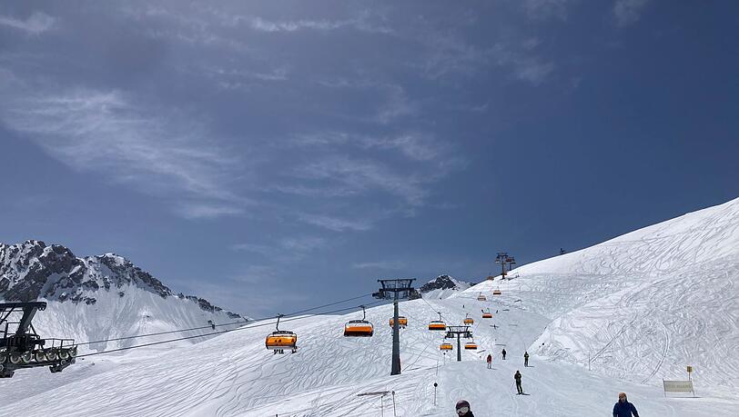 Skifahrer fahren neben einem Lift die Piste hinunter.
