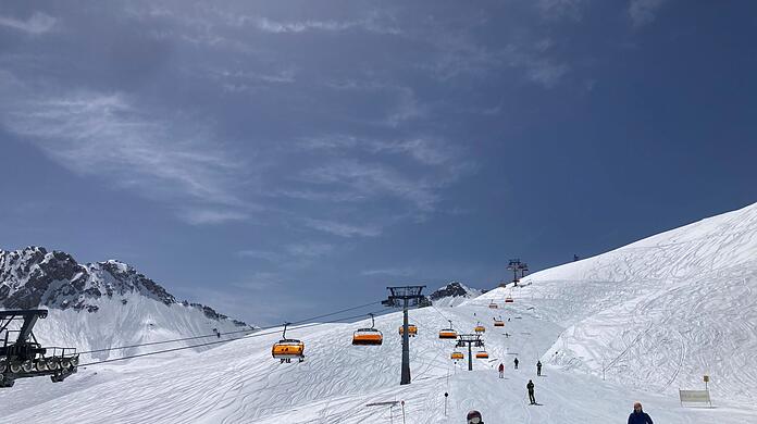 Skifahrer fahren neben einem Lift die Piste hinunter.
