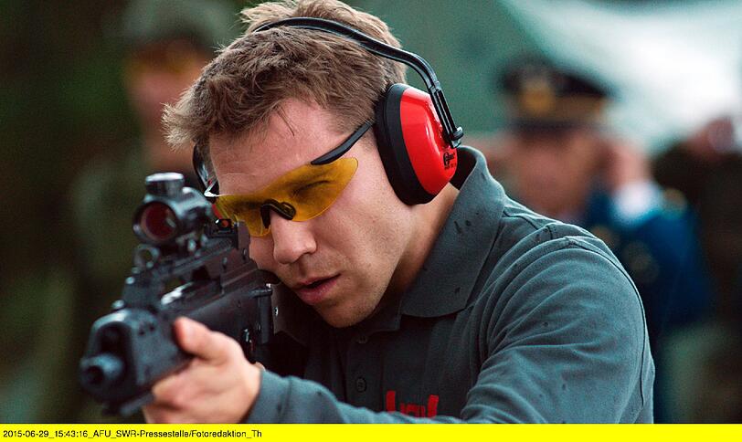 Hanno Koffler als Mitarbeiter des Waffenherstellers HSW. Erführt Kunden die Waffen vor im Film "Meister des Todes".