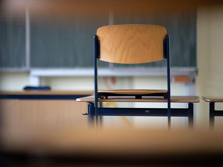 Im leeren Klassenzimmer einer Realschule steht ein Stuhl auf dem Tisch.