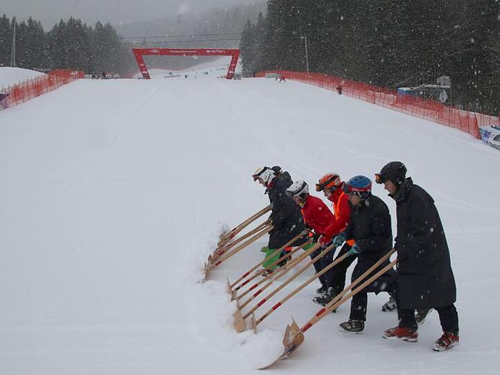 Helfer bringen Schnee aus dem Zielbereich beim Weltcup in Garmisch-Partenkirchen. Foto: Stephan Jansen