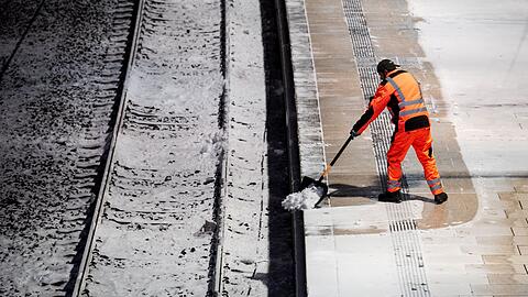 Ein Mann r&auml;umt am Hauptbahnhof in Hamburg auf einem Bahnsteig Schnee.