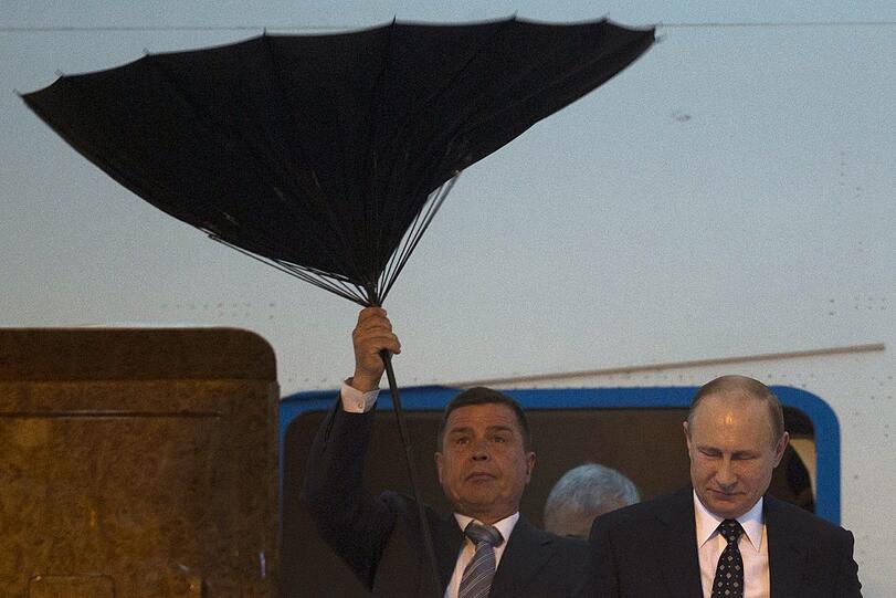 Windiger Staatsbesuch: Ein Security von Kreml-Chef Wladimir Putin kämpft mit dem Regenschirm in Schanghai, China.