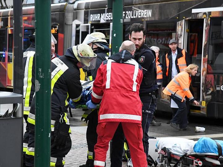 Einsatzkräfte versorgen Verletzte, nachdem eine Seniorin in Essen an einer Straßenbahn-Haltestelle in eine Menschenmenge gefahren war.