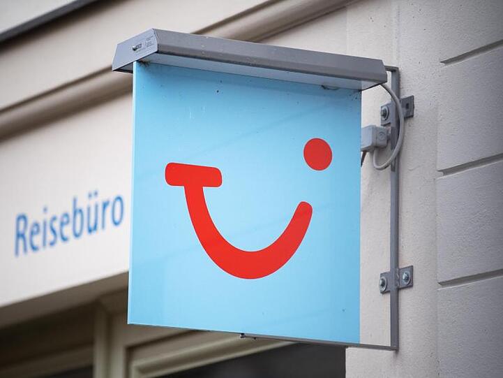 Das Logo des Reiseunternehmens TUI neben einem geschlossenen Reisebüro.