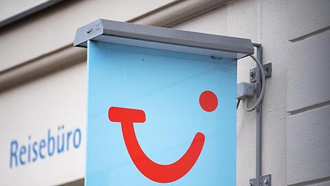 Das Logo des Reiseunternehmens TUI neben einem geschlossenen Reisebüro.