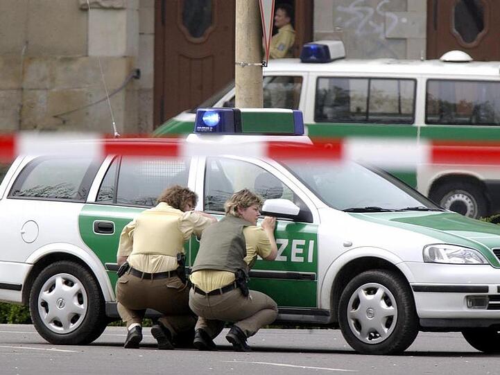 Polizeibeamte gegen hinter ihrem Wagen vor dem Gutenberg-Gymnasium in Erfurt in Deckung. (Archivfoto vom 26.04.2002)