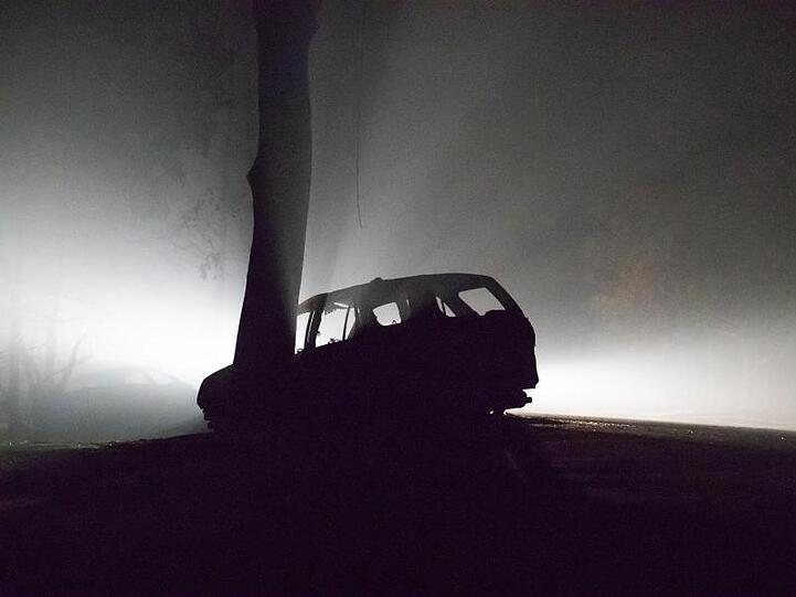 Wie aus einem Horrorfilm: Ein bei den kalifornischen Waldbränden ausgebranntes Auto wird in der Nacht von einem patrouillierenden Feuerwehrfahrzeug beleuchtet.