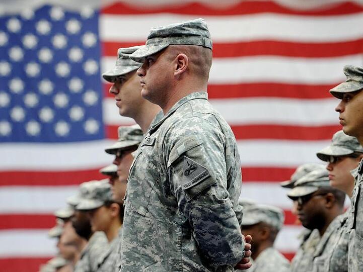 US-Soldaten stehen nach ihrer Ankunft auf der US-Airbase in Wiesbaden-Erbenheim vor einer US-Flagge. Foto: Frank May/dpa/Archivbild