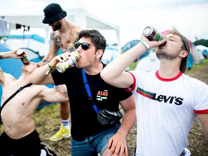 Drei junge Festivalbesucher versuchen sich im Synchron-Trinken.