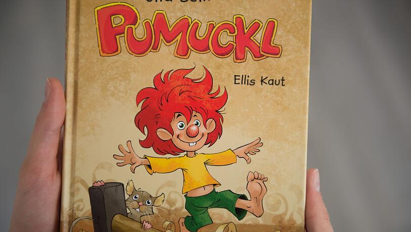 Eine Frau hält ein Pumuckl-Buch in den Händen.