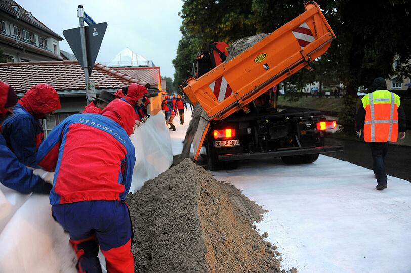 Bergwachtler helfen entlang des Mangfallkanals in Kolbermoor bei Rosenheim (Bayern) einen Damm zu bauen.