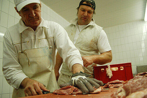Für manche Spieße wird das Fleisch sogar noch von Hand geschnitten. Der Chef (rechts) erklärt einem Mitarbeiter, wie&rsquo;s richtig geht.