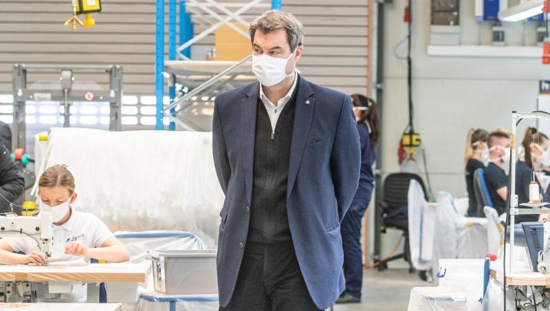 Markus Söder mit einer Mundschutzmaske in einer Produktionshalle des Automobilzulieferers Zettl. Foto: Armin Weigel/dpa Markus Söder mit einer Mundschutzmaske in einer Produktionshalle des Automobilzulieferers Zettl. Foto: Armin Weigel/dpa