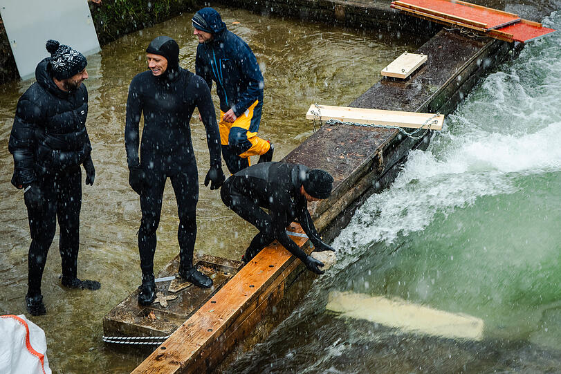 Mit angetäuten Brettern, die im Eisbach versenkt werden, entsteht schon mal eine Miniwelle. Dann kommt der Kies rein.