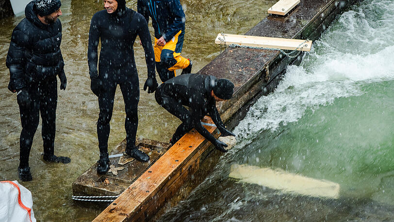 Mit angetäuten Brettern, die im Eisbach versenkt werden, entsteht schon mal eine Miniwelle. Dann kommt der Kies rein.
